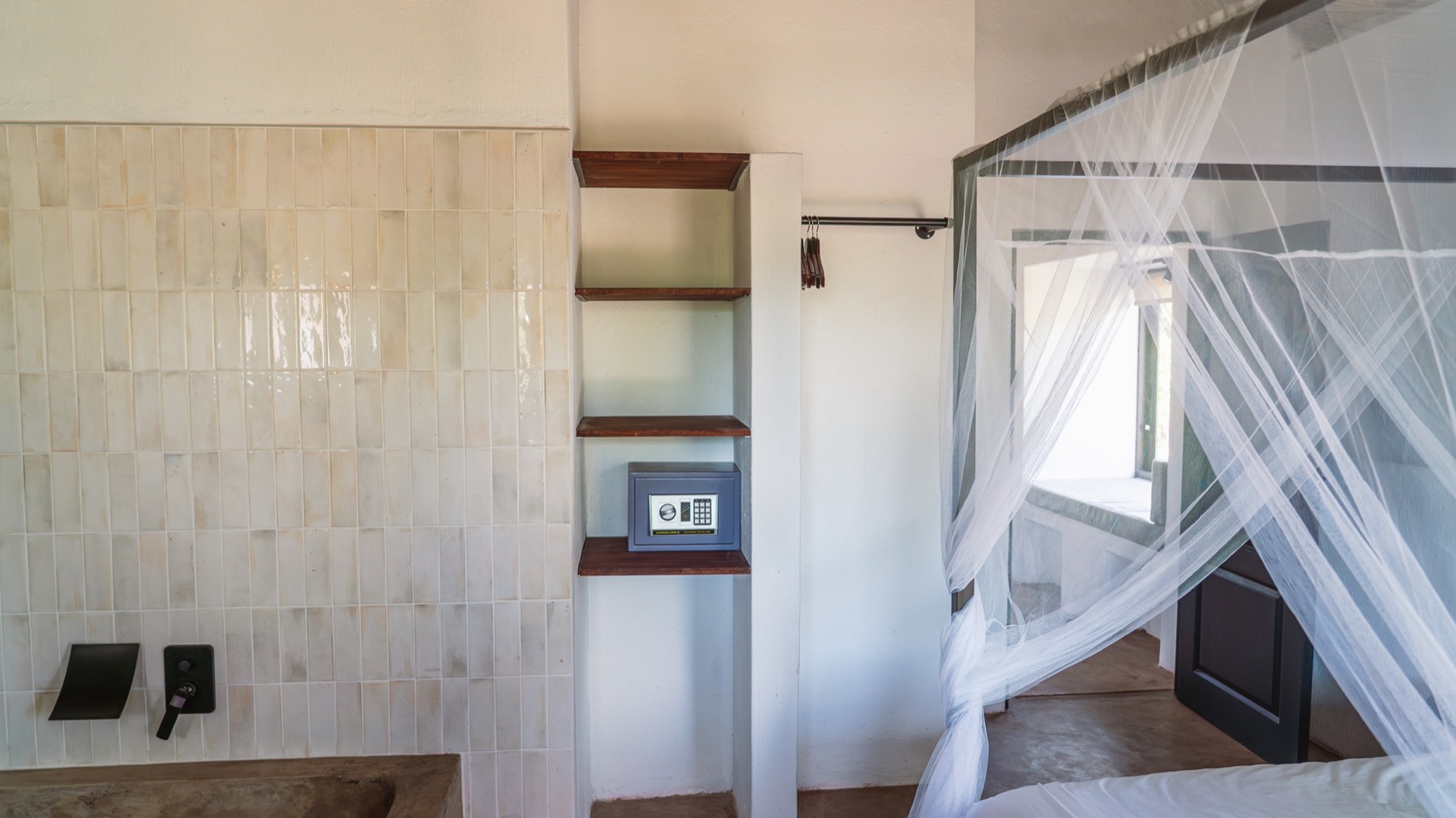A canopy bed draped in mosquito netting beside the en-suite