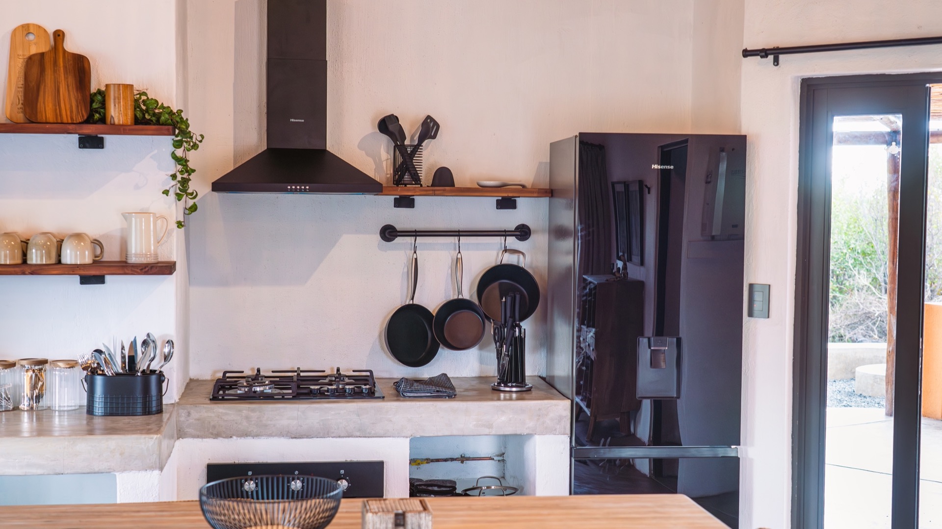 Kitchen with gas hob, hanging pans and a black fridge